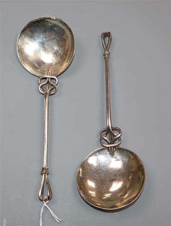 A pair of Arts and Crafts white metal serving spoons, with pierced scroll stems and openwork terminals, 17.2cm.